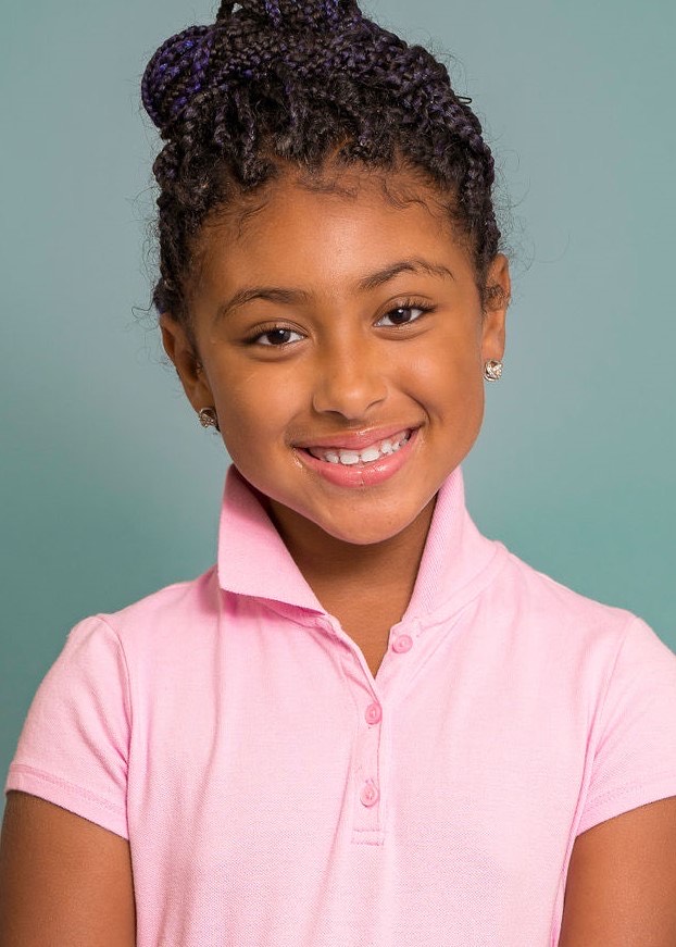 Eleaya Neveah studio headshot, smiling in a pink polo shirt against a teal background