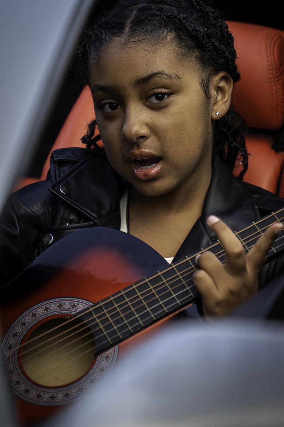 Eleaya Neveah singing and playing guitar in a leather jacket